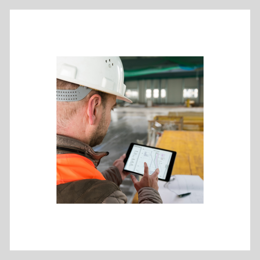 Profile of a man in a hard hat holding an iPad looking at SKM software in an unfinished building